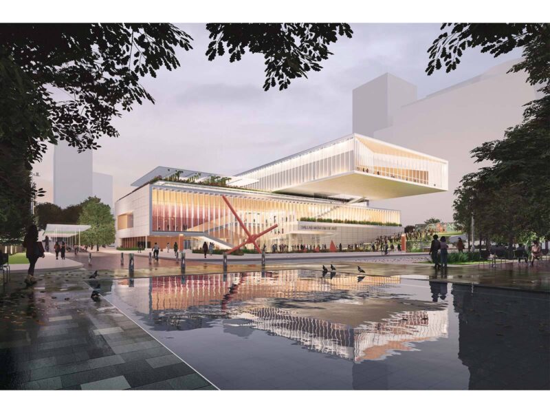 Dusk render of the illuminated museum facade with a cantilevered upper volume, reflected in a still pool in the foreground